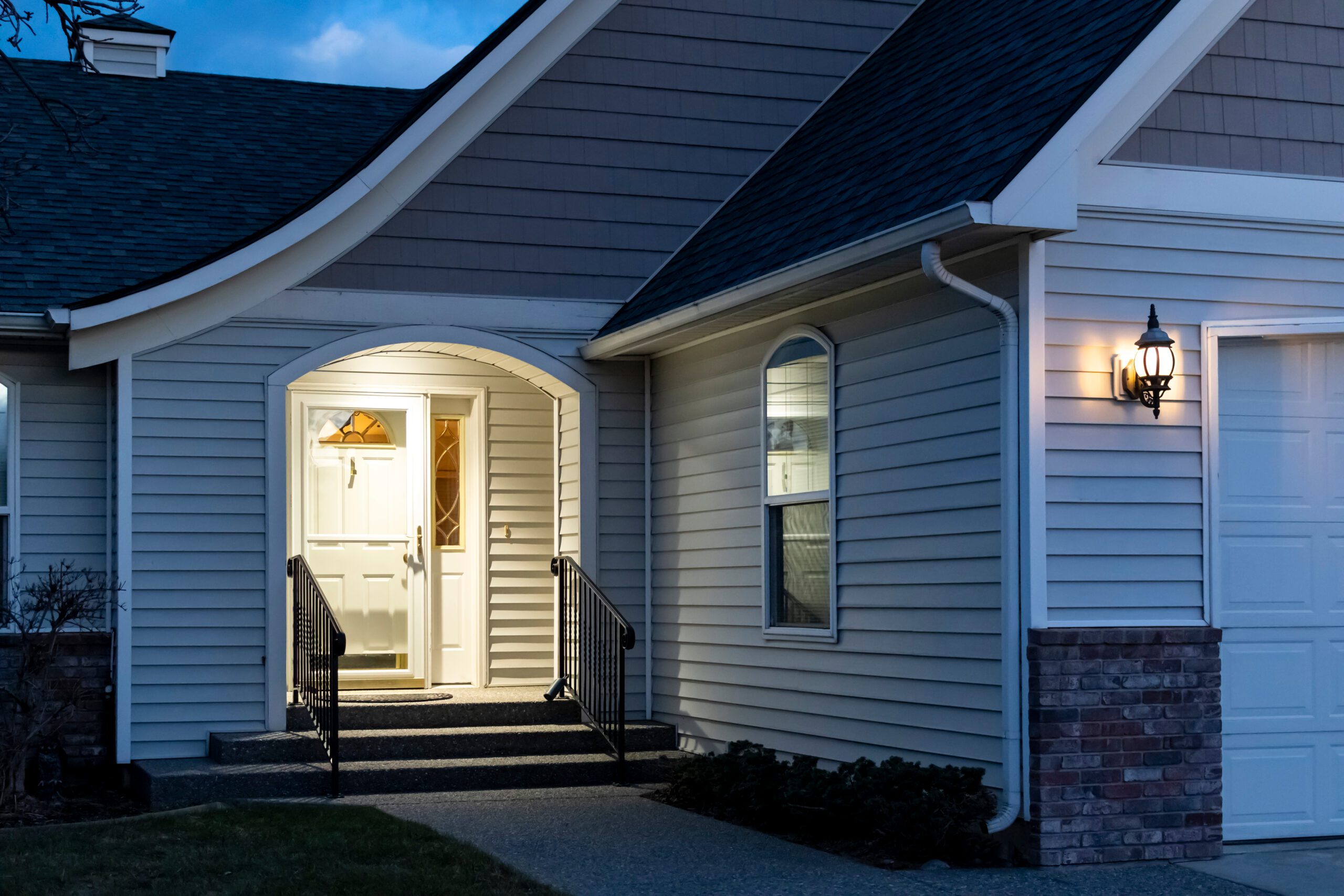 Porch light illuminates a secure home at dusk, symbolizing safety and strategic lighting for enhanced security.